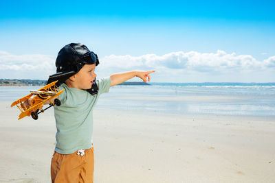 Boy playing at beach against sky