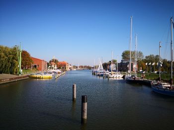 Sailboats moored in harbor against clear sky