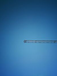 Low angle view of crane against clear blue sky