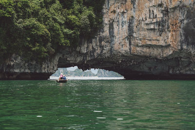 People rowing boat on halong bay under rock formation