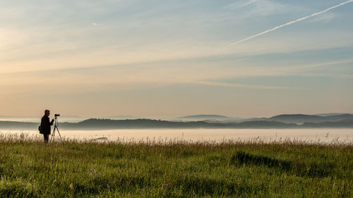 Man standing on field against sky during sunset