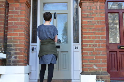 Rear view of man standing against door of building