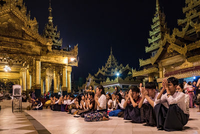 People at temple outside building at night