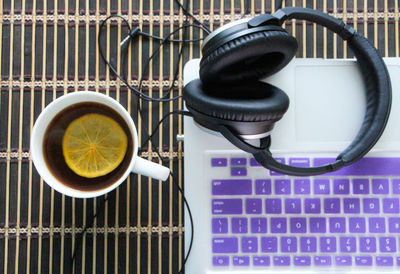 Directly above shot of herbal tea by laptop and headphones on table