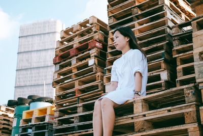 Full length of woman sitting by stack against sky