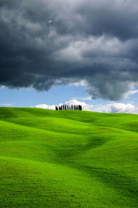 Scenic view of rolling landscape against stormy clouds