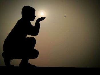 Silhouette man photographing against sky during sunset