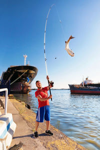 Man with fishing rod and fish in industrial harbor