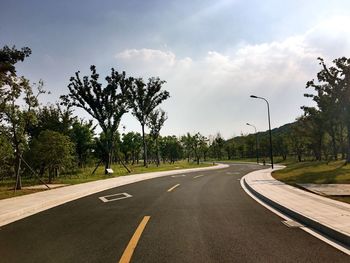 Empty road amidst trees against sky