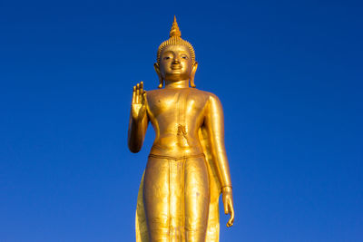 Low angle view of statue of buddha against blue sky