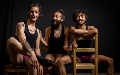 Happy friend sitting on chair against black background