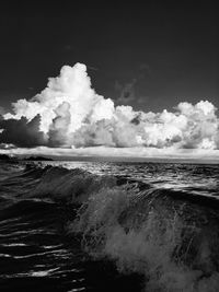 Sea waves splashing on shore against sky