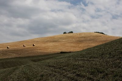 Hay bales on field against sky