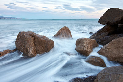 Scenic view of rocks in sea against sky