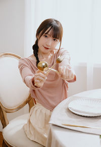 Young woman drinking milk while sitting on sofa at home