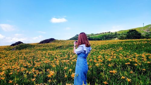 Full length of woman standing on field against sky