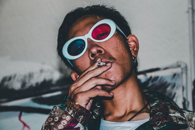 Portrait of young man wearing 3-d glasses while smoking cigarette