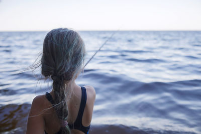 Rear view of woman in sea against sky