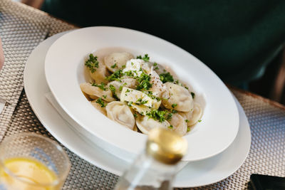 Dumplings with sour cream and herbs in a plate.
