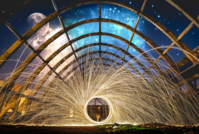 Man spinning wire wool against sky at night