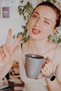 Portrait of young woman holding coffee at home
