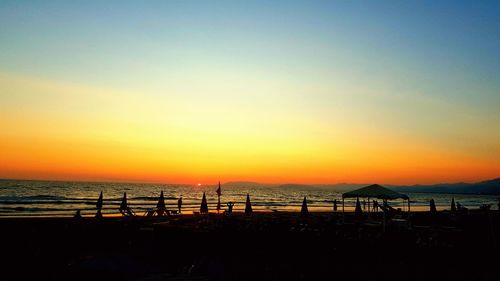 Silhouette people on beach against sky during sunset