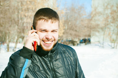Portrait of smiling man in warm clothing talking on mobile phone