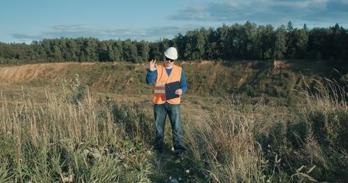 Man standing on field by trees against sky