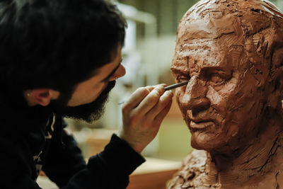 Focused sculptor finishing a clay head in an art studio