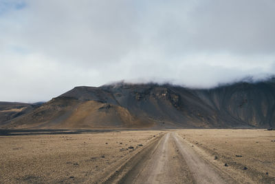 Empty road in desert against sky