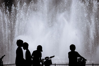 Silhouette people at fountain against sky at night