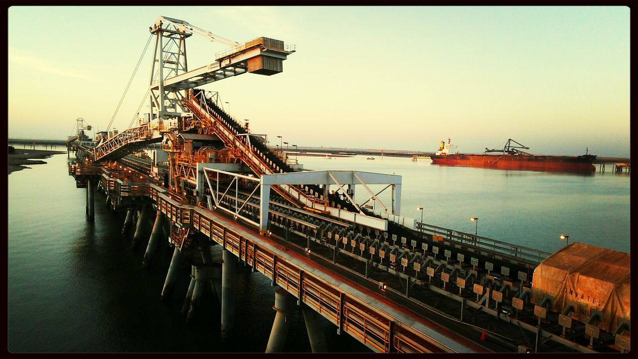 water, sea, nautical vessel, transportation, clear sky, transfer print, harbor, boat, moored, mode of transport, auto post production filter, pier, built structure, sky, crane - construction machinery, commercial dock, outdoors, mast, waterfront, no people