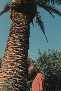 Rear view of woman by tree against clear sky