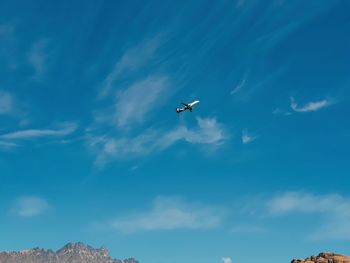 Low angle view of airplane flying against blue sky