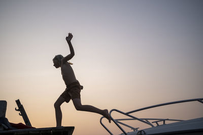 Low angle view of boy jumping on jetty