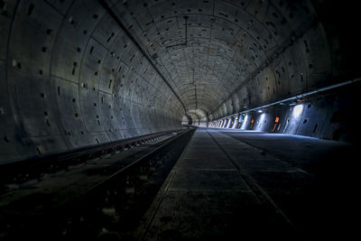 Railroad tracks in illuminated tunnel