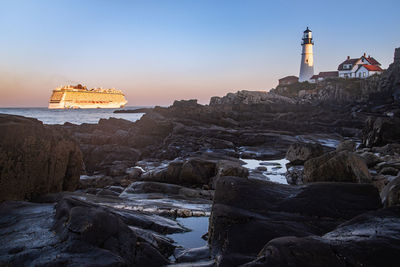 Lighthouse by sea against sky