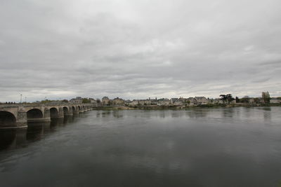 Bridge over river against sky in city