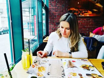 Young woman reading menu at restaurant