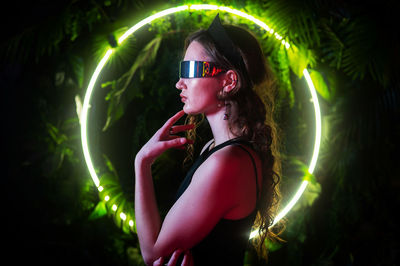 Portrait of young woman wearing sunglasses against sky at night