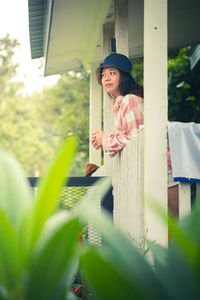 Portrait of young woman standing against plants