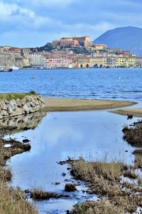 Scenic view of sea by buildings against sky