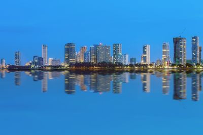 Reflection of illuminated cityscape against sky at night