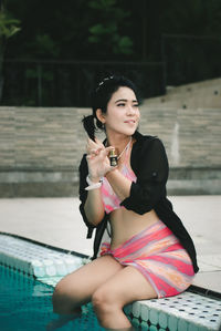 Portrait of young woman sitting in swimming pool