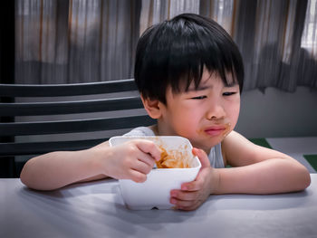 Close-up of cute boy eating food at home