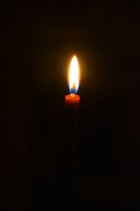 Close-up of candle burning in darkroom