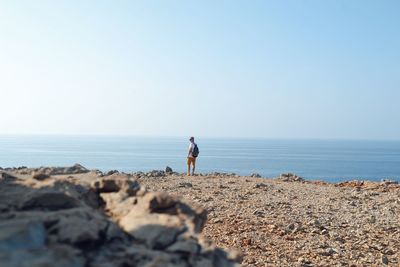 Woman standing on beach against clear sky