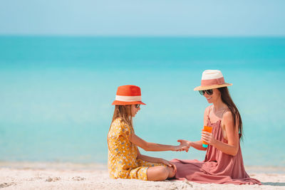 Mother applying sunscreen to daughter at beach