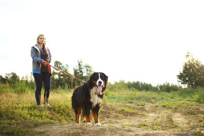 Full length of woman with dog standing on field