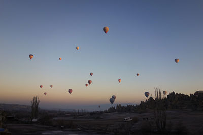 Hot air balloons flying over landscape against clear sky at cappadocia